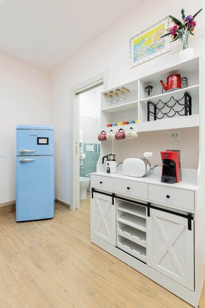 A compact kitchenette with a blue refrigerator, a coffee maker, and a kettle on the counter. - Comfy&Stylish Apt in Rome (Rome)