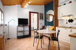 A compact living space with a dining area, kitchenette, and a television. - Modern Apartment Near Centrale Station (Milan)