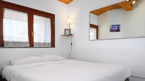 A bedroom with a bed, a nightstand, a lamp, a window with curtains, and a painting on the wall. - Modern Apartment Near Centrale Station (Milan)