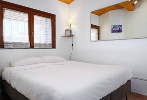 A bedroom with a bed, a nightstand, a lamp, a window with curtains, and a painting on the wall. - Modern Apartment Near Centrale Station (Milan)