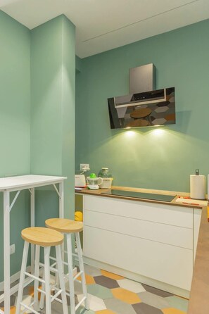 Eine Küche mit weißer Arbeitsplatte, Barhocker und einer Mikrowelle.