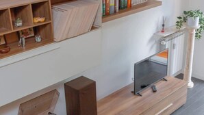 A modern living room with a wooden entertainment unit, a flat-screen TV, speakers, and a coffee table. - Holi Rome - Bright&Comfy apt inTrastevere (Rome)
