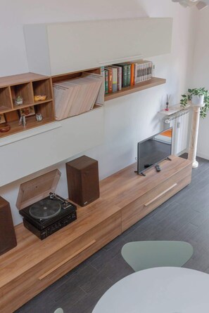 Ein modernes Wohnzimmer mit einer Holzeinrichtungsanlage, einem Flachbildfernseher, Lautsprechern und einem Couchtisch.