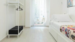 A minimalist hotel room with a bed, a wardrobe, and a bathroom visible through a glass door. - Holi Rome - Bright&Comfy apt inTrastevere (Rome)