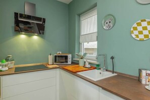 A kitchen with a microwave, toaster, sink, and a window with blinds. - Holi Rome - Bright&Comfy apt inTrastevere (Rome)