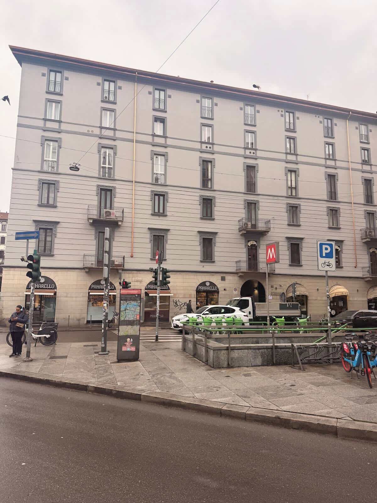 Ein mehrstöckiges Gebäude mit Geschäften im Erdgeschoss, einem Parkschild und einer Fußgängerampel.