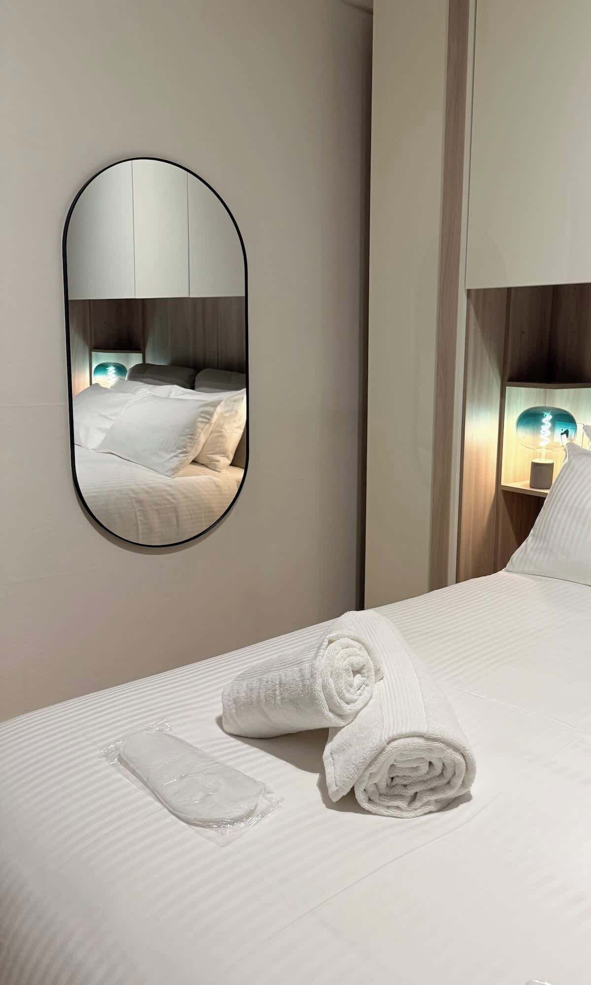 Ein Hotelzimmer mit einem Bett, einem runden Spiegel und einer Nachttischlampe.