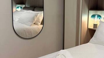 Ein Hotelzimmer mit einem Bett, einem runden Spiegel und einer Nachttischlampe.