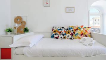 Une chambre à coucher bien rangée, avec un lit, des oreillers, une table de chevet avec une lampe et des œuvres d’art accrochées au mur.