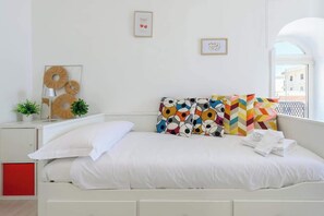 Ein ordentlich eingerichtetes Schlafzimmer mit einem Bett, Kissen, einem Nachttisch mit Lampe und Wandbildern.