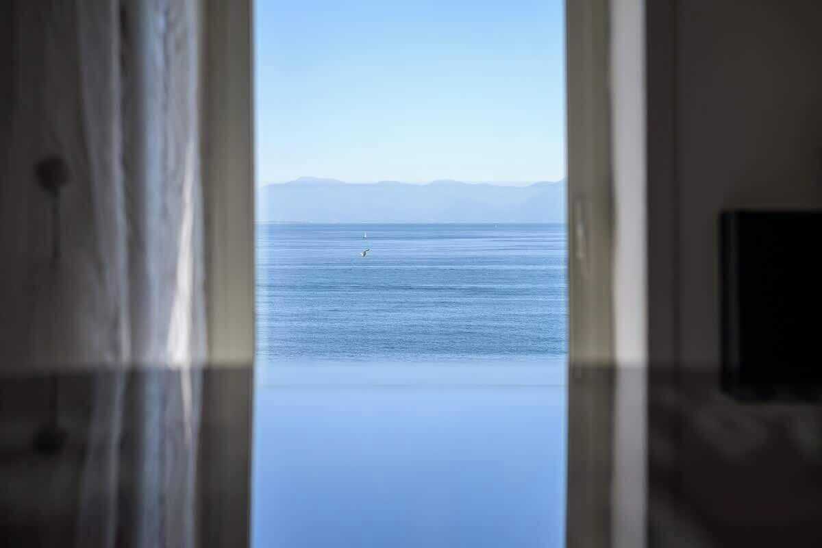 A view through a doorway to a body of water with a distant landmass.