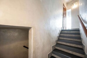 Eine Treppe mit Handlauf, eine Tür am Obergeschoss und einer Wandleuchte.