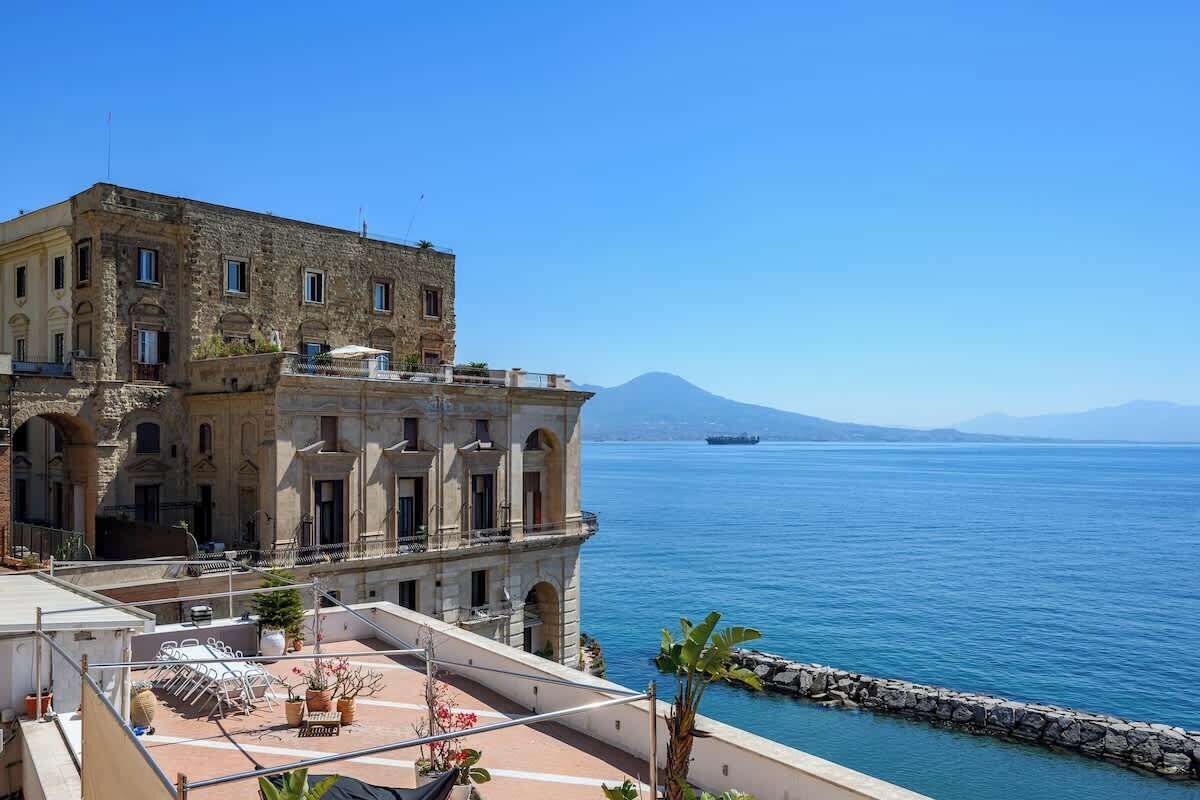 A building with a balcony overlooking a body of water and a distant mountain.