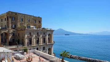 Un edificio con un balcone che si affaccia su un corpo d'acqua e una montagna in lontananza.