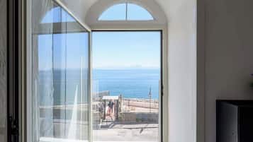 Une porte ouverte donnant sur la mer et un bâtiment doté d’une arche blanche.
