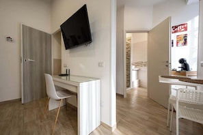 A modern room with a glass desk, a white chair, a flat-screen TV mounted on the wall, and a coffee machine on the counter. - Studio 5 min to Napoli Centrale (Naples)