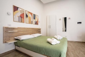 Ein modernes Schlafzimmer mit einem Bett, einem Kleiderschrank und Kunstwerken an der Wand.