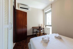 Ein Hotelzimmer mit Bett, Schreibtisch, Stuhl, Klimaanlage und einem Fenster mit Aussicht.