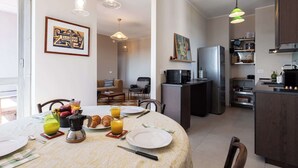 A modern kitchen with a dining area, featuring a refrigerator, microwave, and a coffee maker on the counter. - Skyline View - Design Apartment - Bicocca Metro (Milano)