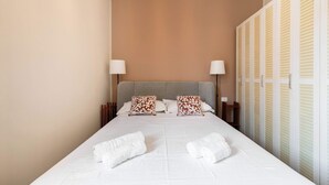A hotel room with a bed, two bedside lamps, a headboard, a wardrobe, and two towels. - Skyline View - Design Apartment - Bicocca Metro (Milano)