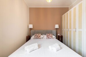 Ein Hotelzimmer mit einem Bett, zwei Nachttischlampen, einer Kopfteil, einem Schrank und zwei Handtüchern.