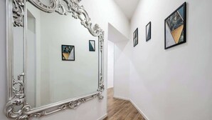 A hallway with a large ornate mirror, a wooden floor, and framed artworks on the walls. - Central House, Standard room · Central House, Standard room (Naples)