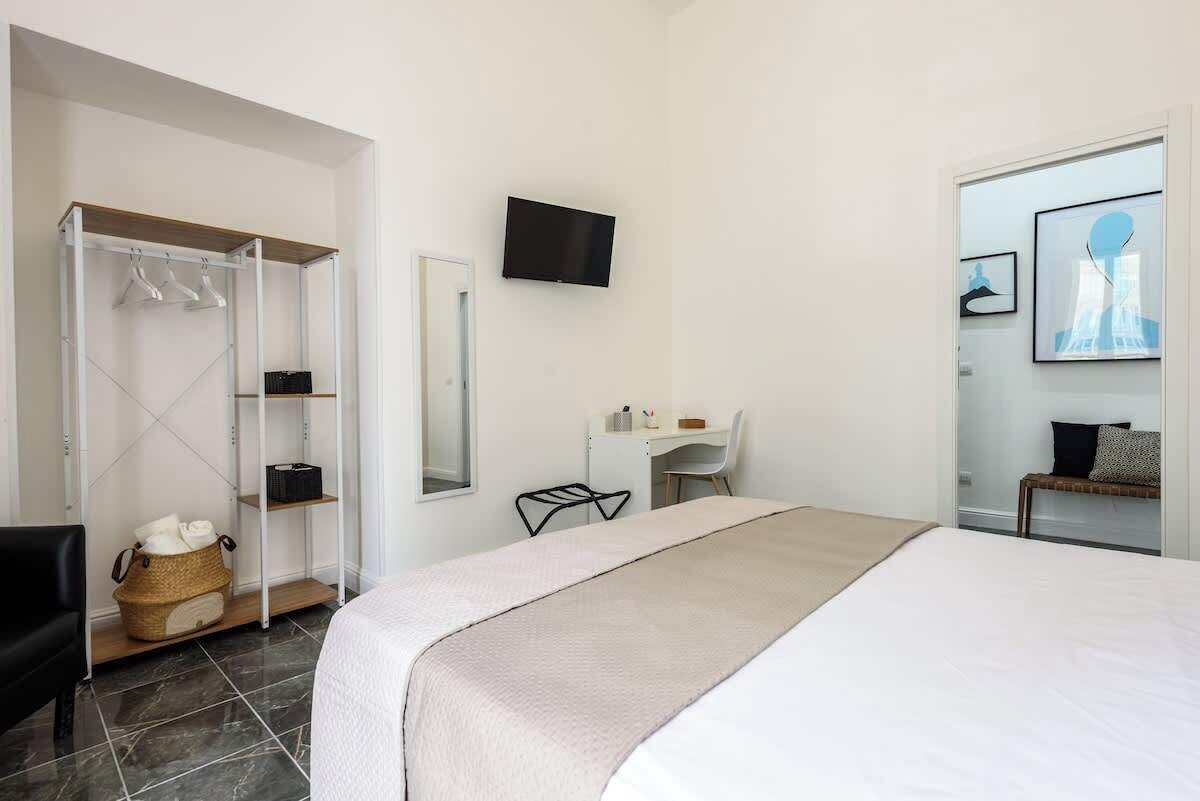 A hotel room with a bed, a desk, a chair, a TV, a wardrobe, and a bathroom.