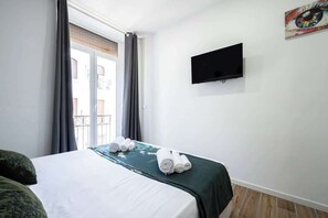A hotel room with a bed, a flat-screen TV, and a balcony view. - Superior · balcony, private kitchen · Centrale (Naples)