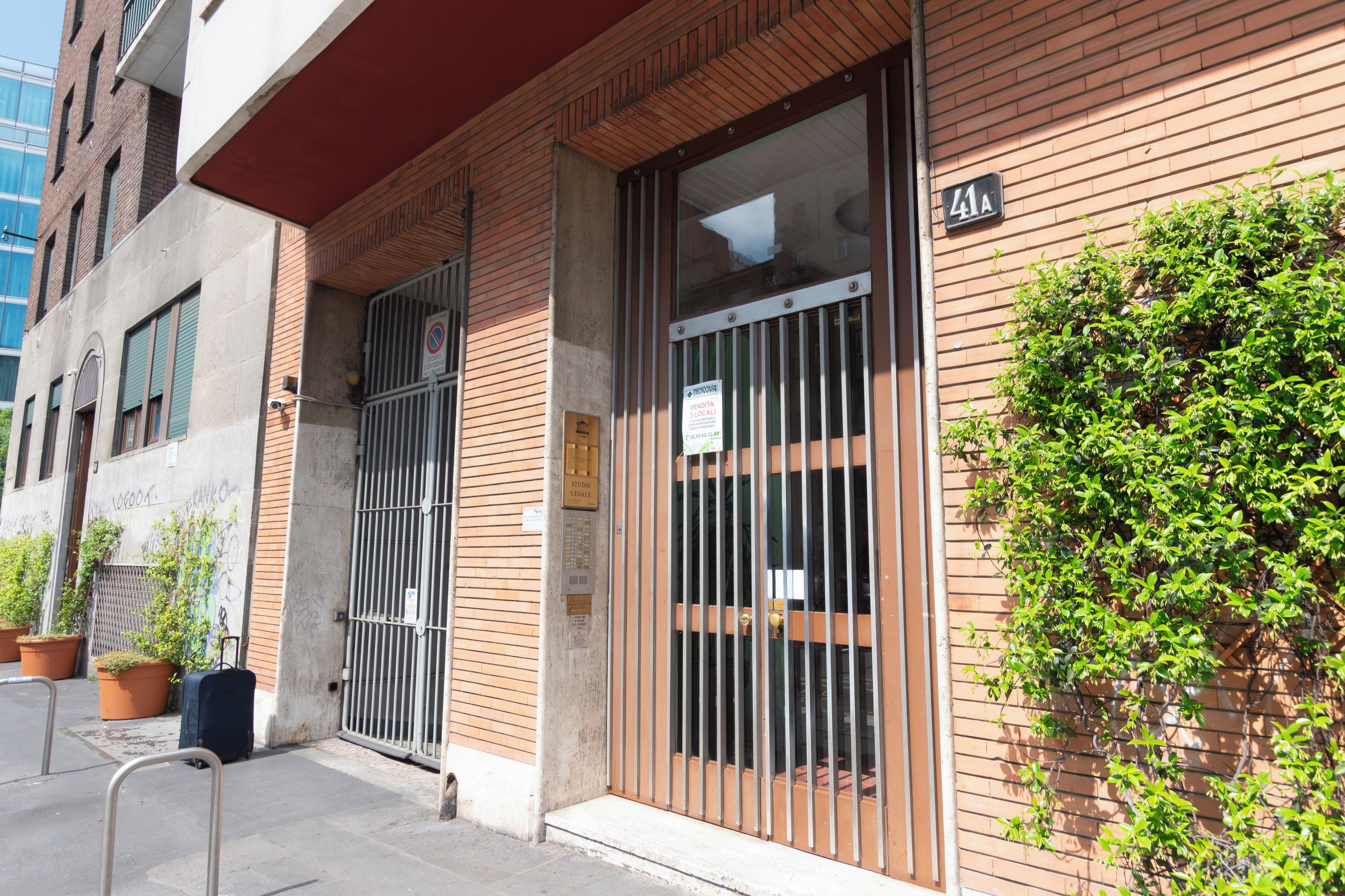 A building with a brick facade, metal gates, and a sign indicating a studio legalese.