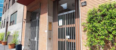 A building with a brick facade, metal gates, and a sign indicating a studio legalese.