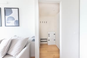 Ein modernes Interieur mit einer weißen Couch, abstrakter Wandkunst, Holzboden und einem weißen Schrank mit Stauraum.