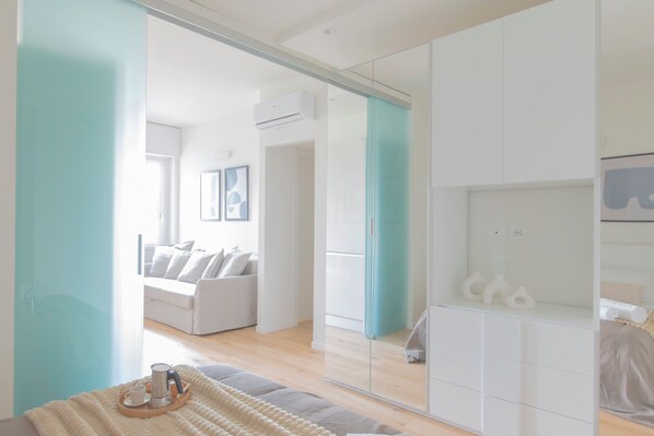 Una camera da letto moderna con un letto, un comodino, uno specchio e un armadio.