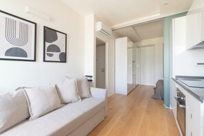 A modern living room with a sofa, a kitchen with a stove, and a hallway leading to another room. - Between Central Station & Porta Nuova - 1 bedroom (Milan)