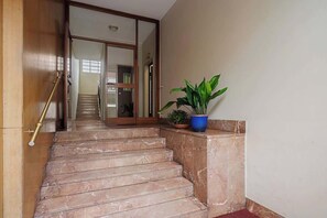 A marble staircase leading to a room with a sliding glass door, a potted plant, and a wooden handrail. - Vicino Malpensa, Tribunale e Ospedale @Busto (Busto Arsizio)
