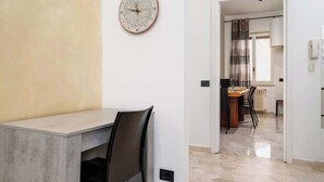 Ein modernes Interieur mit Essbereich, einer Wanduhr und Blick in die Küche.