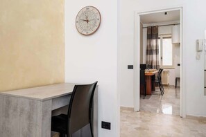 A modern interior with a dining area, a clock on the wall, and a view into the kitchen. - Vicino Malpensa, Tribunale e Ospedale @Busto (Busto Arsizio)