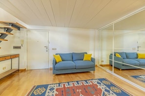 A living room with a sofa, a patterned rug, a wooden bench, and a glass partition. - Monti - Stunning Loft in the Heart of Rome's Monti (Rome)