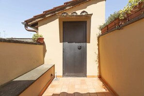 A narrow alleyway leading to a door with a small step and a potted plant on the left. - Monti - Stunning Loft in the Heart of Rome's Monti (Rome)