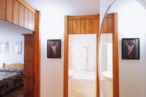 A bedroom with a bed, a wooden wardrobe, and a bathroom with a shower and sink. - Appartamento vista Matterhorn (Breuil-Cervinia)