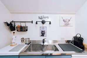 A kitchen with a stainless steel sink, a coffee dispenser, and a wall-mounted light fixture. - Appartamento vista Matterhorn (Breuil-Cervinia)