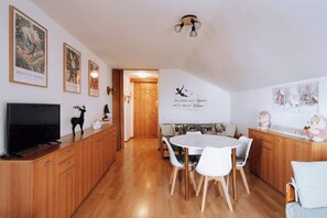 A dining area with a round table and chairs, wooden cabinets, a television, and wall art. - Appartamento vista Matterhorn (Breuil-Cervinia)