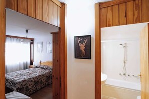 A bedroom with a bed, a wooden wardrobe, a framed deer head artwork, and a bathroom with a bathtub and shower. - Appartamento vista Matterhorn (Breuil-Cervinia)