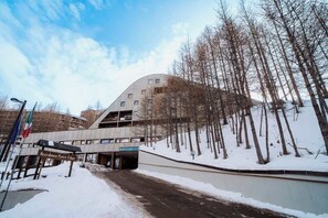 A modern building with a curved facade, a sign reading 'Residence Petit Tibet,' and a snowy landscape with bare trees. - Appartamento vista Matterhorn (Breuil-Cervinia)