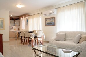 A living room with a glass coffee table, a sofa, and a dining area with chairs and a table. - Premium Penthouse with Stunning Views and Free Gated Parking next to Metro (Μενεμένη)