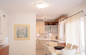 A kitchen with white cabinets, a dining table with chairs, and a framed picture on the wall. - Premium Penthouse with Stunning Views and Free Gated Parking next to Metro (Μενεμένη)