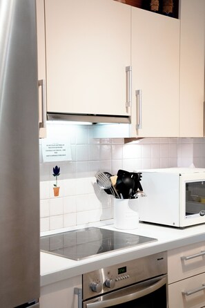A kitchen with white cabinets, a microwave, and a stove. - Premium Penthouse with Stunning Views and Free Gated Parking next to Metro (Μενεμένη)