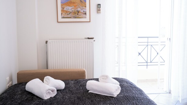 Et hotelværelse med seng, radiator, et indrammet billede og udsigt til en port.