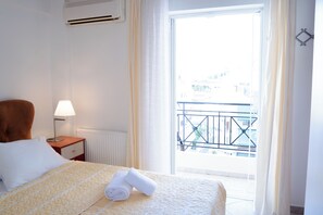 Hotellihuone, jossa on sänky, yöpöytä, lamppu, patteri ja näkymä parvekkeelle, jossa on kaide.