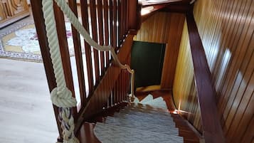 Una escalera de madera con barandilla de cuerda y un rellano alfombrado.