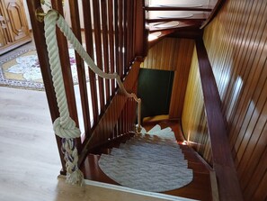 A wooden staircase with a rope handrail and a carpeted landing.